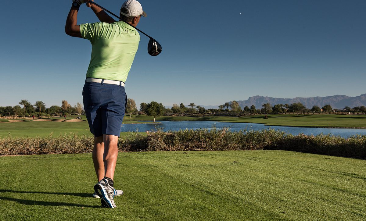 Man swinging a golf club on a golf course