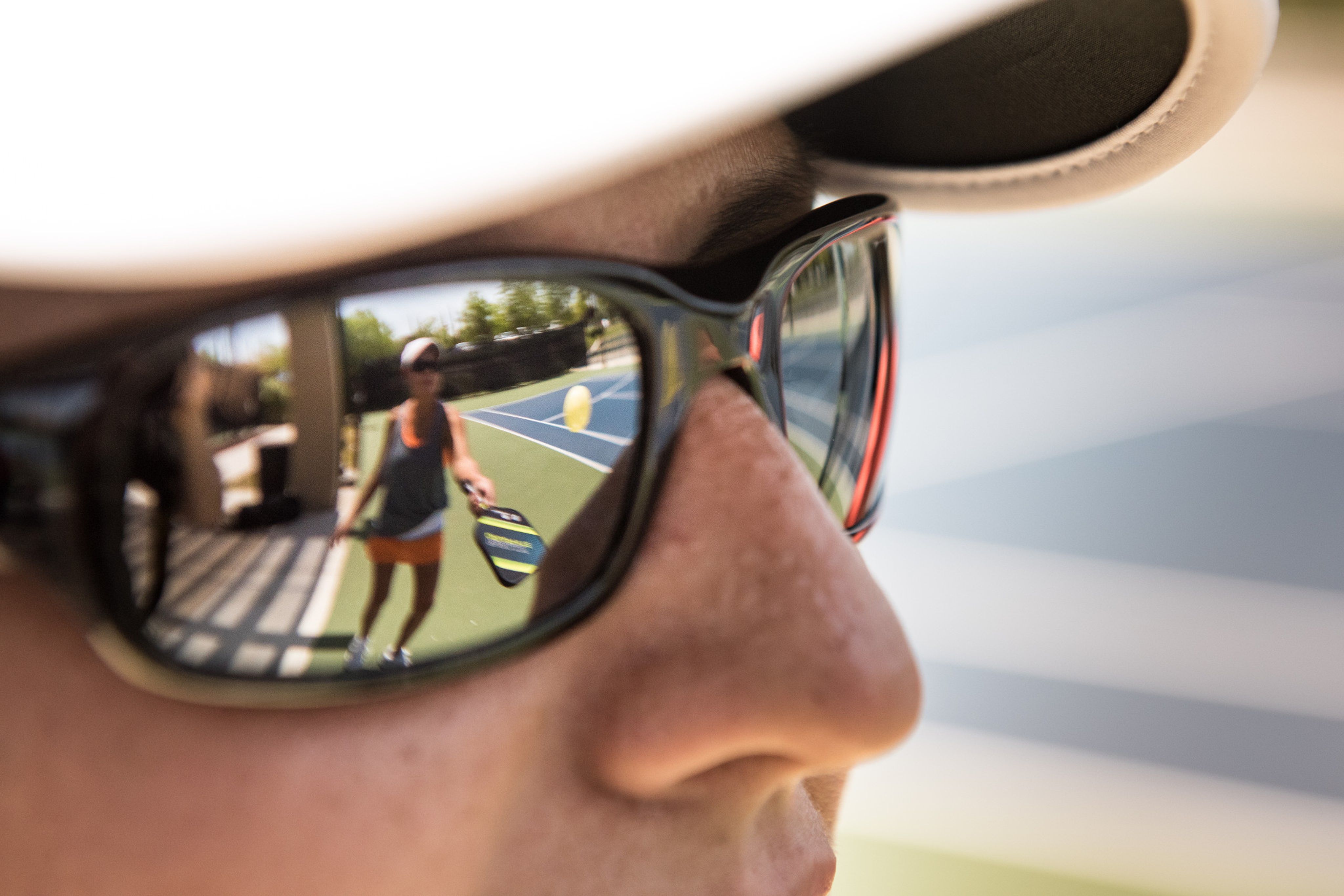 Lady with a gal in the sunglasses reflection playing pickleball